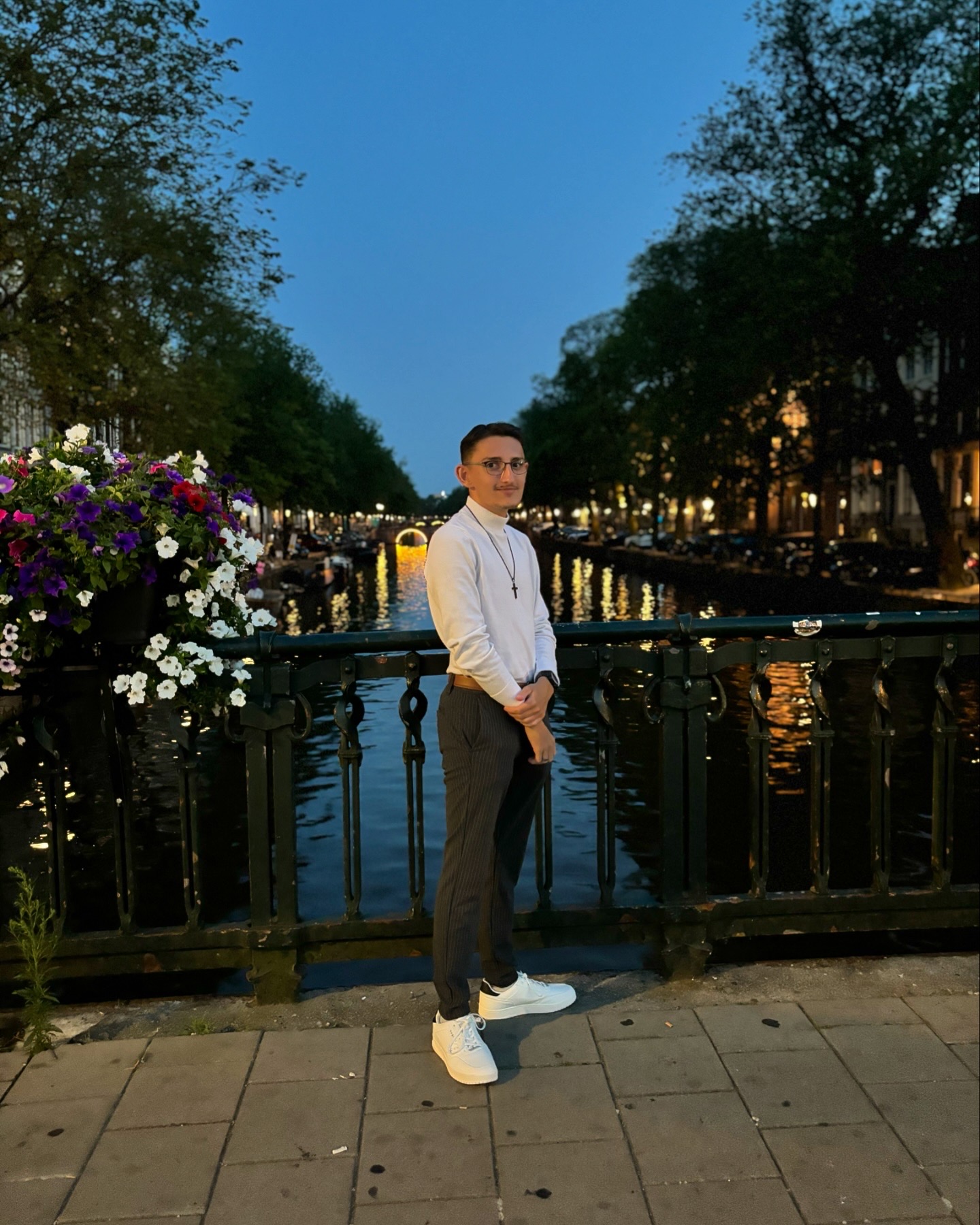 Person auf Brücke über beleuchtetem Kanal bei Dämmerung