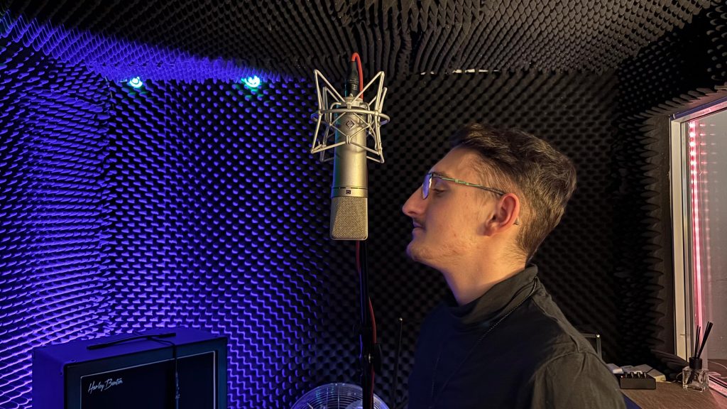 Person vor Mikrofon in schallgedämpftem Aufnahmeraum